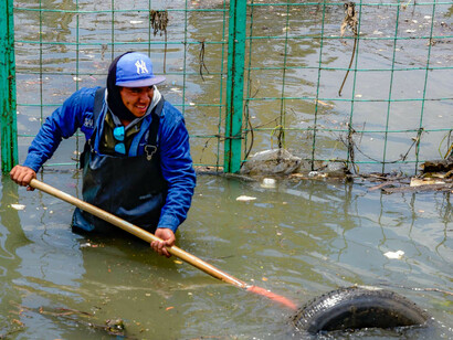 Men clearing debris in a flood-stricken urban neighborhood, reflecting the escalating dangers of climate-driven extreme weather