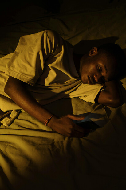 A person sitting alone with a smartphone, absorbed in the screen and separated from their surroundings