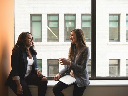Two women talking by a window