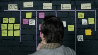 A professional reviewing a project workflow board, representing the importance of building systems that support consistent execution