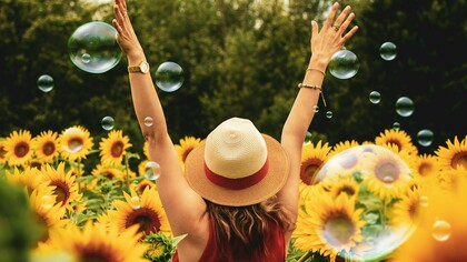 Una donna gioiosa di schiena in un campo di girasoli. La gioia è un'emozione universale, un inno di felicità che risuona attraverso l'anima umana in una sinfonia di colori e sensazioni