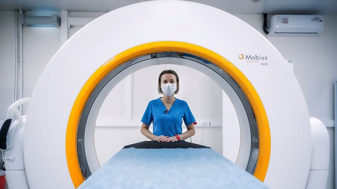 A female doctor confidently poses beside an MRI machine, showcasing the advanced technology used in modern medical imaging for accurate diagnoses