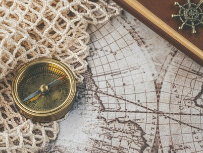 An old brass compass lying across a historic chart, reflecting the imperial vision that guided Russia from Peter the Great to the present day