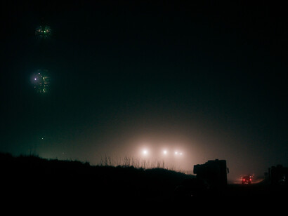 A car drives towards a group of ominous lights on a foggy night