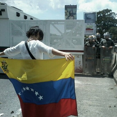 Manifestante enfrenta a la policía sosteniendo la bandera de Venezuela durante las protestas contra el gobierno de Nicolás Maduro en 2014