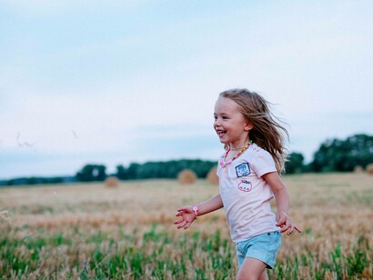 A young child full of happiness is running in the field towards someone