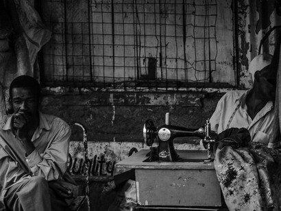 The man's steady gaze and the woman's focused work embody the commitment to uplift themselves and their community through hard work and creativity