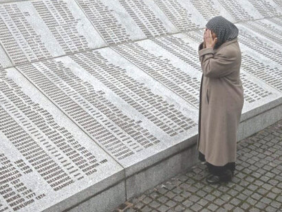 Mujer llora frente a los nombres de las víctimas en el Monumento del Genocidio de Srebrenica