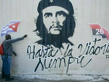 Homem em frente à pixação com rosto de Che Guevara. A obra pode ser vista como um signo aberto, um “texto” incompleto que precisa da interação e da subjetividade do espectador para finalmente ficar completa