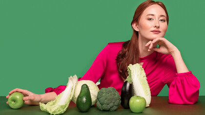 Stunning redhead woman posing with chlorophyll-rich green vegetables for vibrant portrait