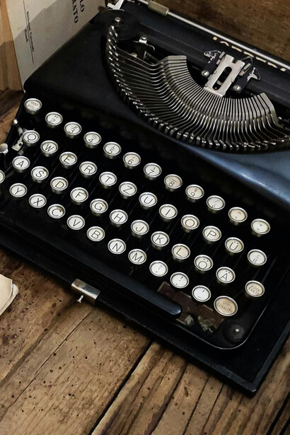 Máquina de escribir y unos libros sobre una mesa de madera