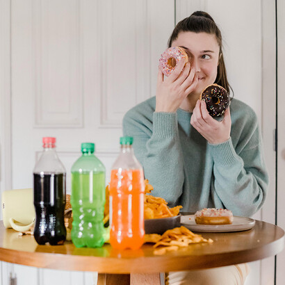 Mulher com donuts e guloseimas. Há evidências emergentes sugerindo que o consumo excessivo de glicídios pode ter efeitos prejudiciais sobre a saúde cognitiva e o funcionamento cerebral