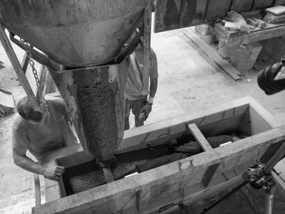 Eugenio Merino, Operarios manejan el vertido de 1150 kg de cemento sobre la escultura de Federico García, fábrica de mobiliario Urbano, Girona, 24 julio de 2024. Cortesía de ADN Galería. Foto por Marc Calleja
