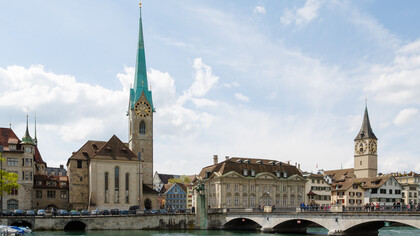 Zurich, Switzerland city view featuring Fraumünster Church, Zunfthaus zur Meisen, Münsterbrücke Bridge, and St. Peter Church in the historic Old Town skyline
