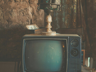 A nostalgic living room scene with a vintage television and soft sunlight streaming through the curtains