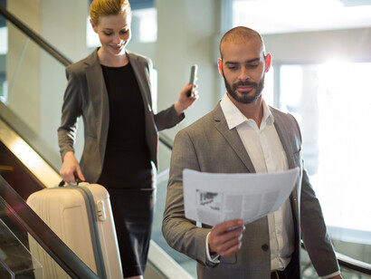 Businesspeople standing on escalator with their luggage