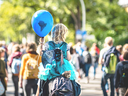 Una niña sobre los hombros de su padre, sostiene un globo con la geografía terrestre