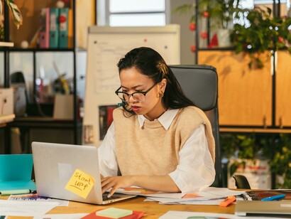 A businesswoman types on her laptop in the office, focused and assertive in her work