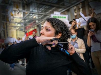 A woman protester cuts her hair in support of Iranian women