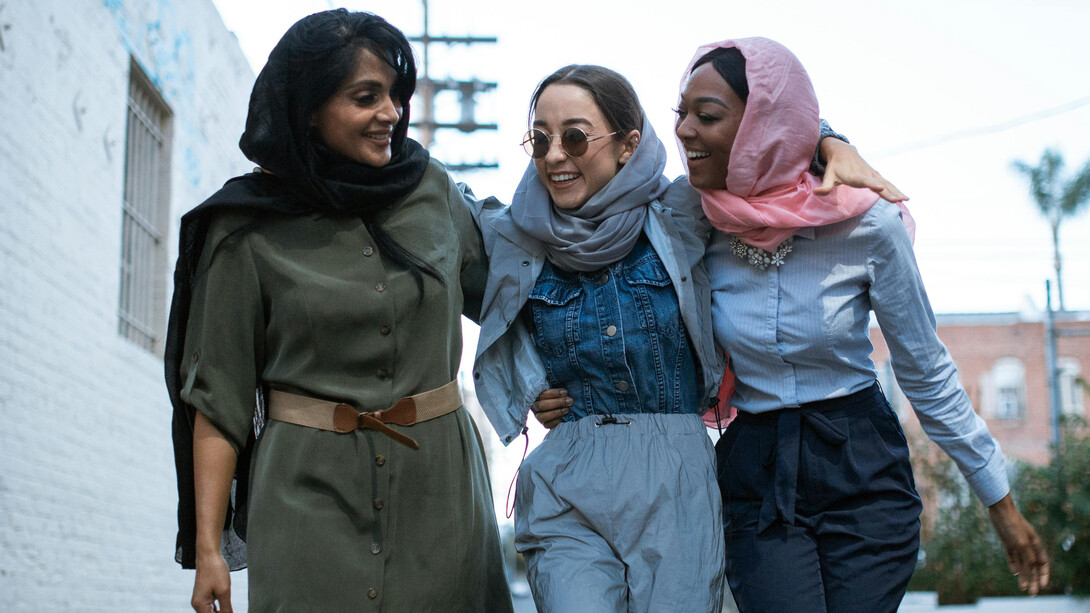 Amigas de diferentes nacionalidades caminham em direção à uma marcha em celebração ao dia da mulher