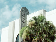An art deco front face of a Miami building, and their notable palm trees