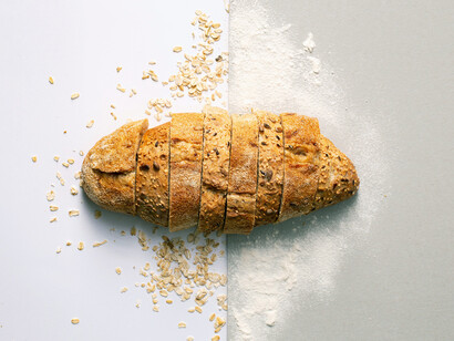 Filone di pane tagliato a fette con farina e briciole di pane