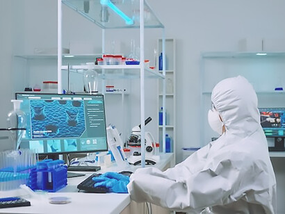 Chemist typing on pc and coworker analysing microscope 