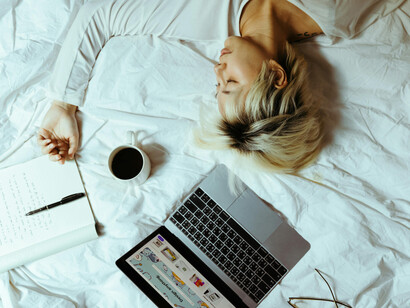 A student asleep on a bed beside a laptop and a cup of coffee, taking a break from studying
