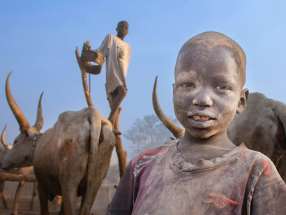 A child surrounded by symbols of ancestral livelihood, reflecting the resilience of East African heritage in the face of modern influence