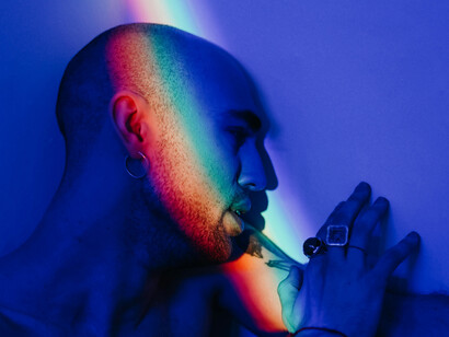 Amidst the darkness, a rainbow touches a man's face