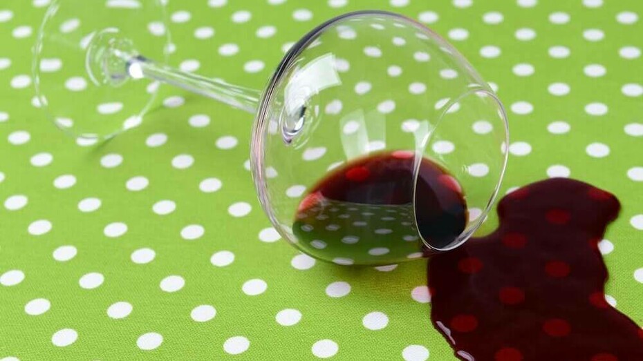 A glass of wine spilt on a brand new green and white polka dotted tablecloth