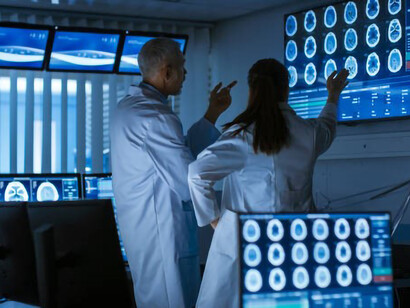 Two neurophysiologists are scrutinizing a scan displayed on screens