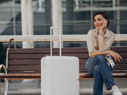 A traveler stands beside her luggage at the airport, waiting for her departure flight