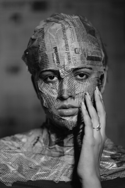 Manchetes e textos espalham-se pelo corpo da mulher, deixando livres apenas os olhos, a boca e o nariz. Ainda cercada por discursos, permanece a possibilidade de olhar e respirar criticamente. Em meio a informação e saturação, o mundo contemporâneo parece exigir constante filtragem do real.