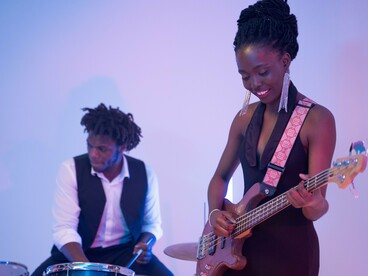 A Black bassist immersed in her performance, reflecting the joy, artistry, and cultural legacy that continue to inspire generations