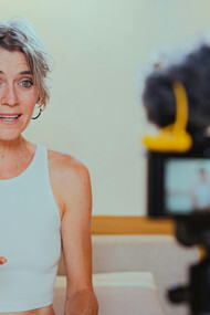 A video camera recording an elderly woman as she vlogs