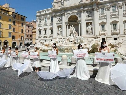 Una dozzina di ragazze vestite da sposa sfilano per il centro di Roma verso la Fontana di Trevi