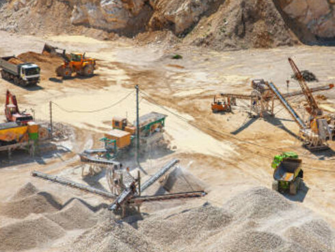 An open-pit quarry is bustling with industrial activity as heavy machinery extracts resources from the surface mine