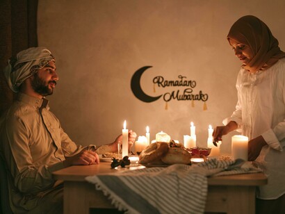 A Muslim couple seated at a candlelit table during Ramadan