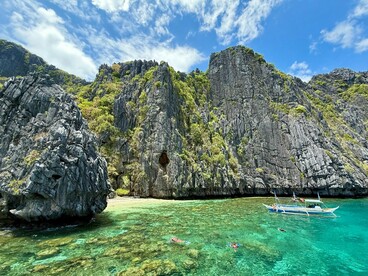 A traditional banca floating beneath El Nido’s towering cliffs, symbolising the strong bond between Filipinos and the sea