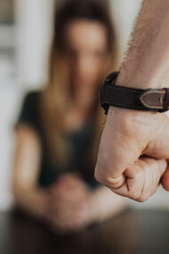 A clenched fist of a person wearing a leather wristwatch, symbolizing domestic violence, fear, and trauma