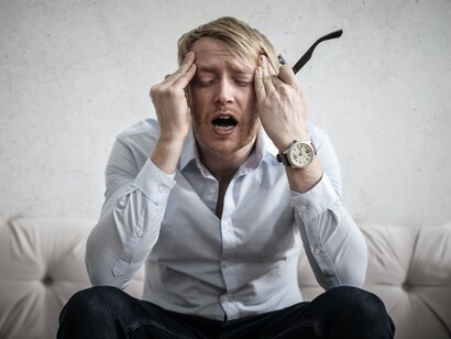 A businessman sitting on a couch, while anxiety is manifesting itself in his daily life