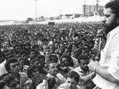 Luiz Inácio Lula da Silva, então dirigente sindical, discursa diante de uma multidão de trabalhadores em uma manifestação. A cena remete ao período em que o movimento operário brasileiro se tornou uma importante força de mobilização social e política e ajuda a compreender as raízes sindicais da trajetória do futuro presidente da República