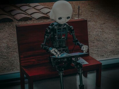 A display of a tiny robot sitting on a bench reading a manual