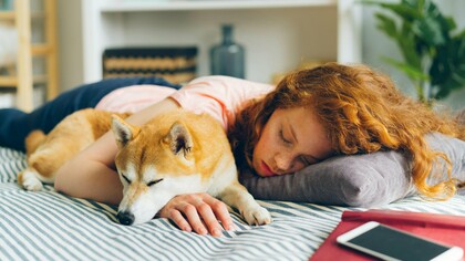 A woman dozing with her dog, capturing the simple, restorative power of pausing in a restless world