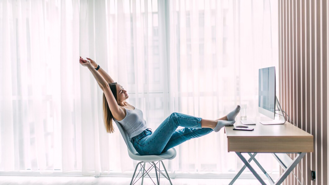 A young female freelancer taking a stretch and relaxing while working on her laptop in a home office