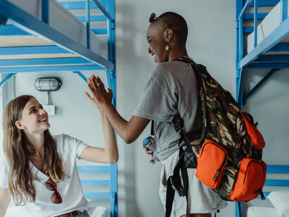 Opposite each other on top bunk beds, two young women chat warmly—sharing stories as part of their exchange student journey