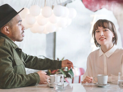 In a different scenario, a woman in a white shirt and a man wearing a hat engage in a joyful speed date, thoroughly enjoying their time together