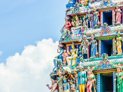 As esculturas coloridas ornamentam a fachada de um templo hindu sob o céu aberto. Em meio às divindades e símbolos sagrados, a vaca permanece como uma das manifestações mais reverenciadas da espiritualidade indiana
