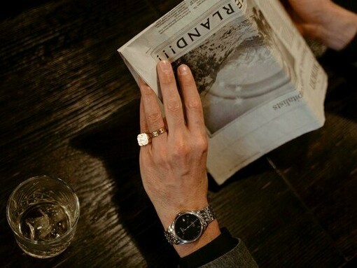 A man wearing his fine watch with an empty glass next to him, representing the luxury Andrew once lived in